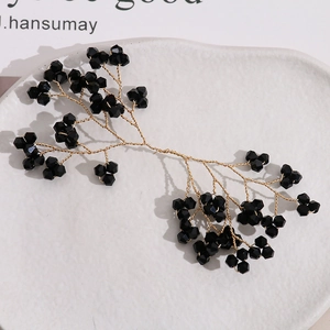 Elegant gold wire hair branch with faceted black crystal beads on a white ceramic plate