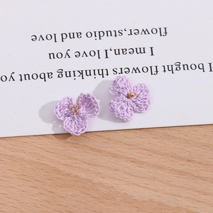 Detailansicht handgefertigter hellvioletter Strickblumen mit Goldperlen und Ringen