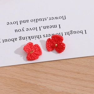 Detail einer roten gehäkelten Blume mit Goldperle auf einer weißen Schmuckkarte