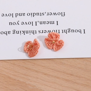 Detail von rosa gehäkelten Blumenanhängern mit Goldringen für DIY-Schmuckzubehör