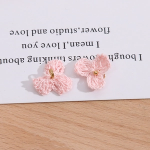 Detail von handgefertigten rosa gestrickten dreiblättrigen Blumen mit goldenen Perlen