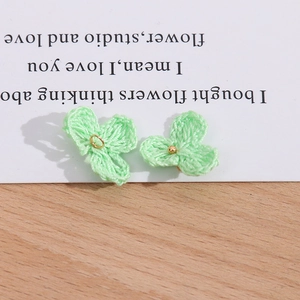 Detailansicht der hellgrünen gestrickten Blütenanhänger mit goldenem Ring und kleinen Perlen
