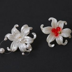Macro detail of pearlescent white petal charms with red beads and faux pearls for DIY