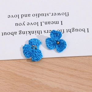 Detailansicht handgefertigter blauer Häkelblumen mit goldenen Perlen für DIY-Schmuck