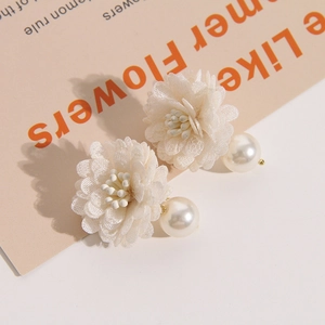 Detailed view of handmade floral earrings with white lace petals and large drop pearls