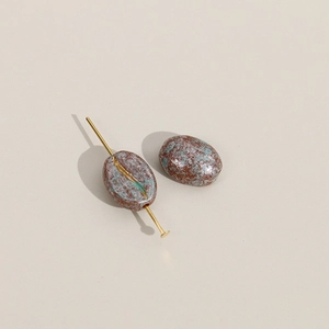Detailopname van acryl kralen in koffieboon-stijl met gouden naald voor DIY-sieraden