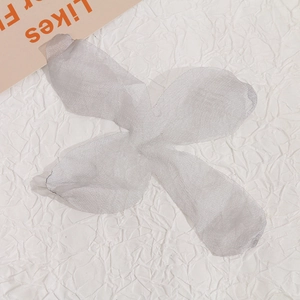 Dettaglio macro di accessorio fiore a quattro petali in maglia argentata per gioielli