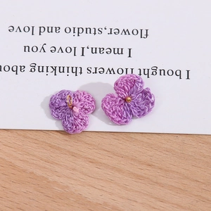 Detail von handgehäkelten lila Blumenanhängern mit goldenen Metallringen für DIY-Schmuck