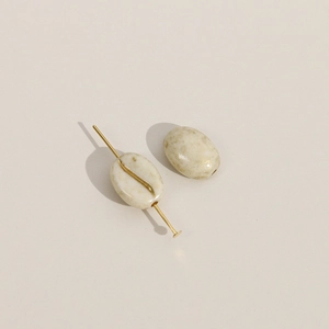 Detail van ovale koffieboon acrylkralen met gouden glitters en metalen pinnen voor DIY