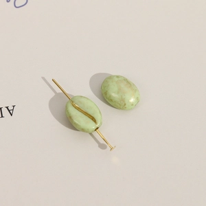 Macro-opname van saliegroene koffieboonkralen met gouden vlekken voor DIY-sieraden