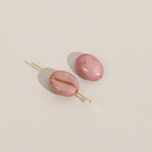 Detail van lichtroze koffieboon kralen met goudmarmeren textuur voor DIY-sieraden maken