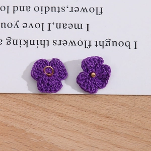 Makroaufnahme violetter handgehäkelter Blumenanhänger mit goldenen Ringen für DIY-Schmuck
