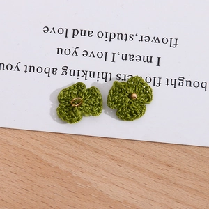 Makroaufnahme grüner handgehäkelter Blumen mit goldenem Ring und Perlenakzenten