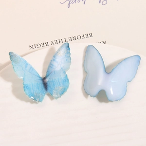 Close-up of DIY resin butterfly charms with blue glitter gradients and soft glossy finish