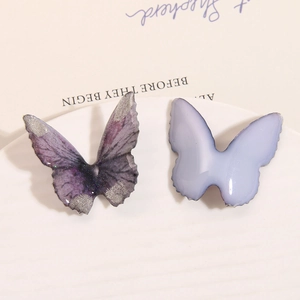 Close-up of resin butterfly charms with glitter and purple gradient for DIY jewelry crafts