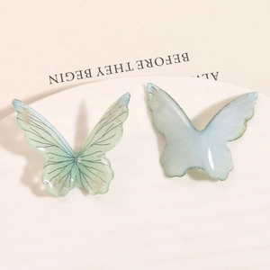 Detailed macro view of two butterfly-shaped resin hair charms with glitter texture