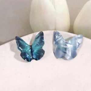 Macro detail of gradient blue 3D butterfly charms with textured metallic luster effect