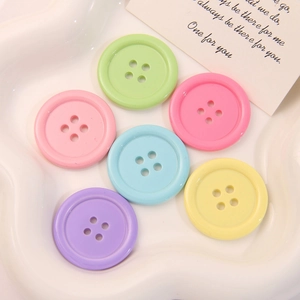 Bottoni rotondi color macaron in resina a 4 fori disposti su vassoio in ceramica bianco