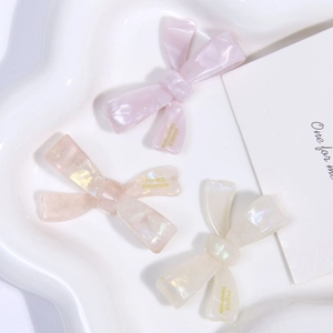 Detailed macro view of handmade cream acetate bow hair clips with marble texture