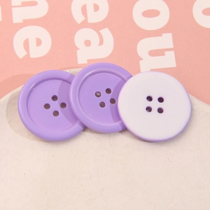 Dettaglio macro di bottoni rotondi in resina lavanda a quattro fori su un vassoio decorativo