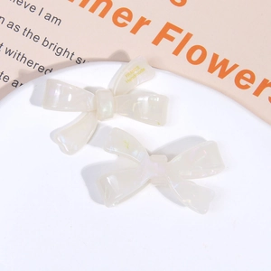 Detail of iridescent cream acetate bow hair clips with France Handmade gold lettering