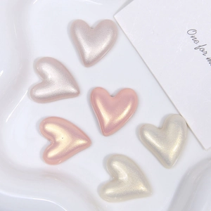 Makroaufnahme von herzförmigen Kunstperlen-Accessoires in Pastellrosa und Goldtönen