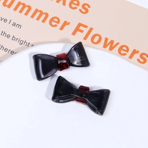 Detail view of handmade black acetate bow hair clips with gold France Handmade lettering