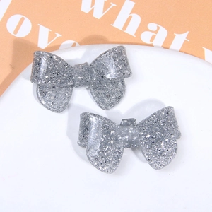 Close-up of two sparkling silver glitter resin bow accessories for DIY hair clips