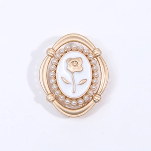 Macro detail of oval vintage rose charm with gold frame and small pearls on white background