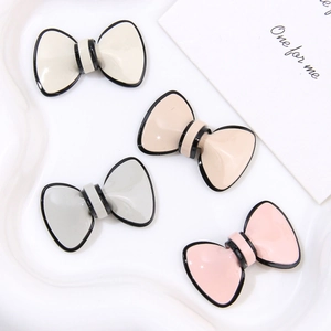 Close-up of four-color acetate bow-knot accessories on a white wavy tray for DIY jewelry