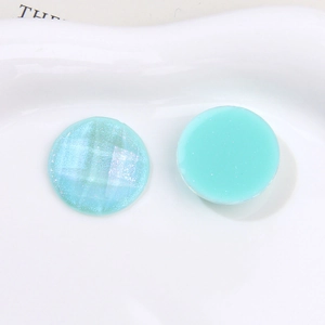 Macro shot of light blue aurora glitter round resin cabochons on a white tray