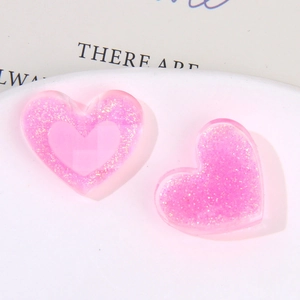 Vista macro di ciondoli a cuore in resina rosa glitterata per accessori gioielli DIY