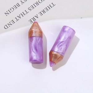 Macro view of purple marble resin pencil charms with golden metallic tips in a ceramic tray