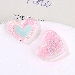Dettaglio macro di ciondoli a cuore in resina glitterata con inserto blu per gioielli