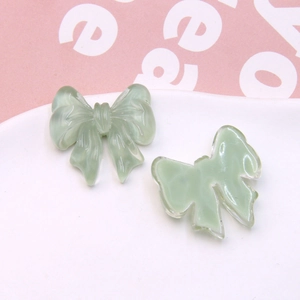 Detail of translucent light green resin bow charms for DIY jewelry and accessories