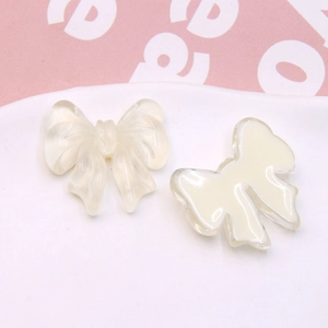 Detail of cream white resin bow charms for DIY jewelry and hair accessories craft