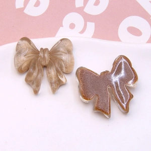 Macro detail of champagne wire-texture and coffee resin bow pendants for DIY jewelry