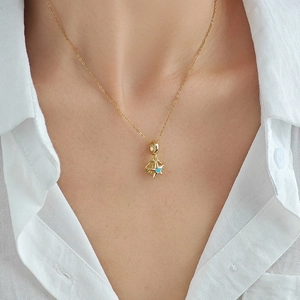 Starfish pendant necklace with blue gemstone and gold chain on model neck