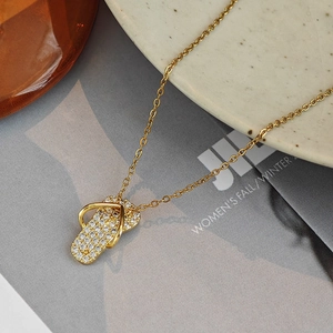 Golden flip-flop pendant necklace with white crystals on a fashion magazine background