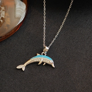 Collier dauphin en argent avec émail bleu et zircon sur fond de tissu noir élégant