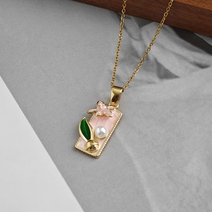 Dettaglio di un ciondolo ovale vintage con smalto floreale rosa, foglia verde e perla