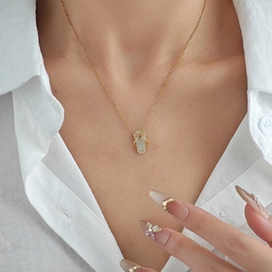 Gold flip-flop pendant necklace with sparkling pavé crystals on elegant female model