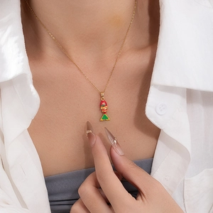 Detail shot of a gold necklace featuring a colorful red, green, and yellow enamel fish pendant