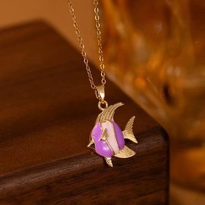 Macro detail of the purple and pink enamel tropical fish pendant on a gold O-chain
