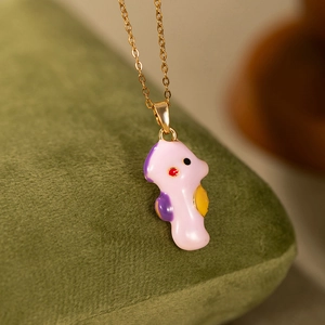 Vue macro d'un pendentif hippocampe rose mignon avec nageoires jaunes sur chaîne dorée