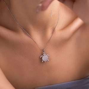 Macro shot of silver turtle necklace pendant paved with sparkling white cubic zirconia