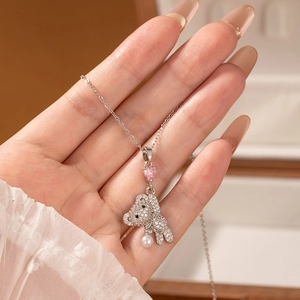 Detailed view of bear pendant with pink heart stone and pearl on silver chain