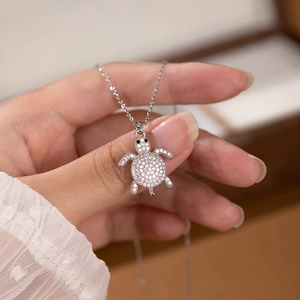 Macro shot of silver turtle pendant encrusted with white crystals held in hand