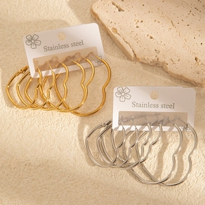Détail de boucles d'oreilles créoles en forme de cœur en acier doré et argenté