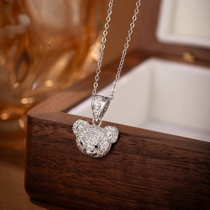 Close-up of a silver bear pendant with sparkling zircon inlay on a jewelry box edge